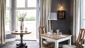 A dining area with a table set for two, a vase with flowers, and a lamp. - A former hotel set deep in the Dorset countryside in a small village (Chettle)
