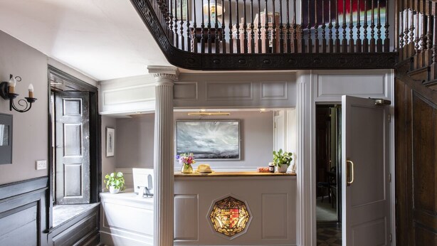 A hallway with a checkered floor, a decorative glass panel, and a staircase with a black railing. - A former hotel set deep in the Dorset countryside in a small village (Chettle)