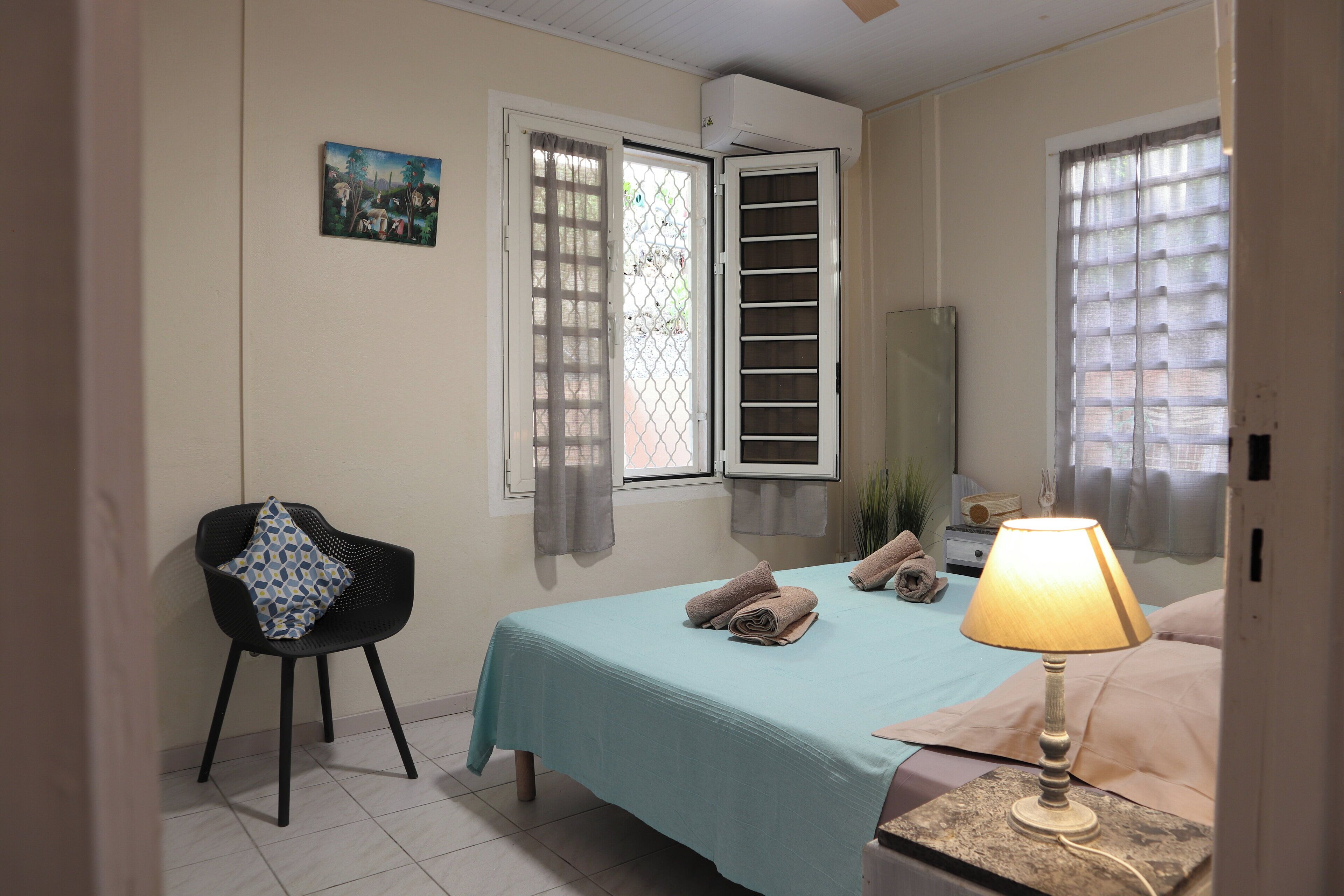 A bedroom with a bed, a chair, a lamp, and a painting on the wall.