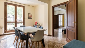 A spacious room with a large table and chairs, a door leading to another room, and a view through a glass door. - Casa Ambrosini - Atena Apt by Wonderful Italy (Bologna)