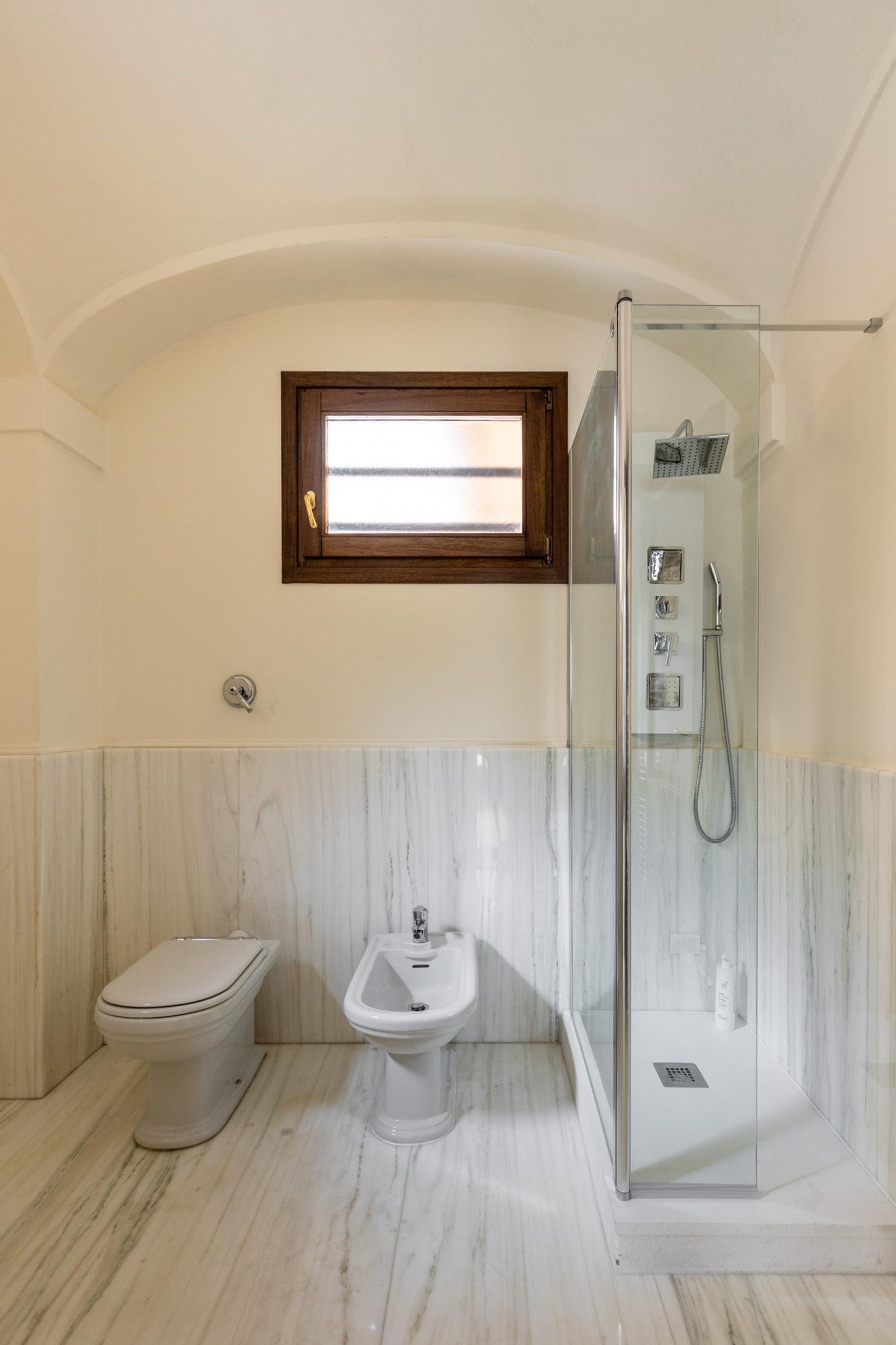 Un bagno con servizi igienici, bidet e doccia con pareti in vetro.