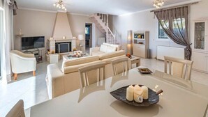 Un salon moderne avec un ensemble de canapés, une table à manger décorée de bougies et un escalier menant à un autre niveau.