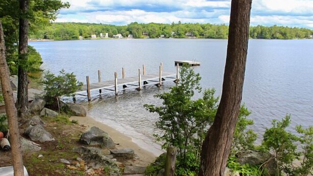 Une jetée au bord du lac, avec une plateforme en bois qui s’avance dans l’eau, entourée d’arbres et de rochers.