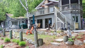 Une maison à deux étages dotée d’une terrasse, d’un espace salon extérieur et d’un chemin en pierre.