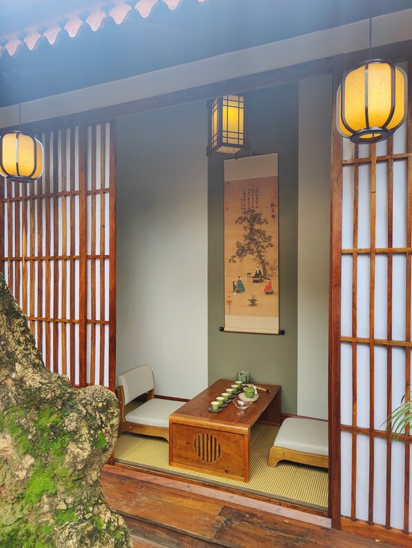 A traditional Japanese room with tatami mats, a low wooden table with green cups, and a calligraphy scroll on the wall.