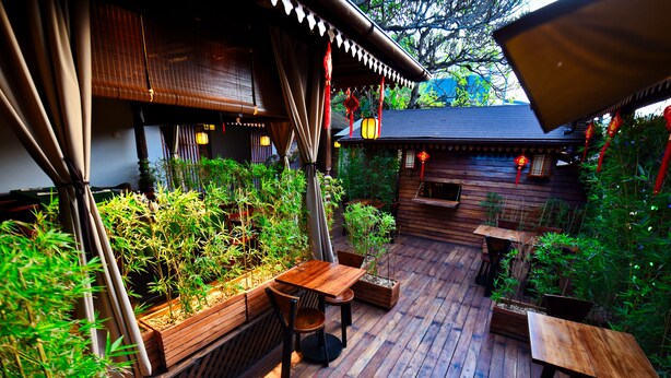 A wooden deck with outdoor seating and planters. - Yushili Hotel & Restaurant (Kampala)