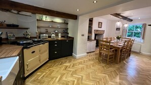 Een keuken met een visgraatvloer, houten kastjes en een eethoek met een tafel en stoelen.