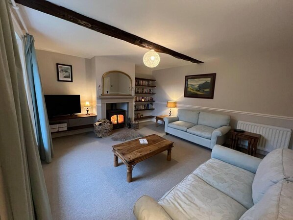 A cozy living room with a fireplace, a sofa, a coffee table, and a bookshelf.