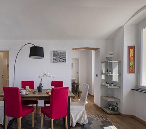 A dining area with a wooden table, red chairs, a black floor lamp, and a potted orchid. - Genova Wonderview by Wonderful Italy (Genoa)