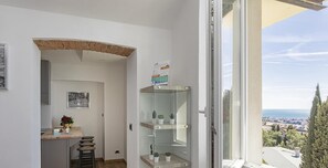A balcony with a glass door, a small table with a vase and a picture frame, and a shelf with plants. - Genova Wonderview by Wonderful Italy (Genoa)
