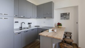 Een moderne keuken met grijze kastjes, een houten aanrecht en een klein eiland met krukken.