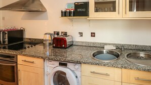 A modern kitchen with a built-in oven, microwave, toaster, and washing machine. - Flat 8 (Bridlington)