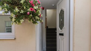 A hallway with a door, a staircase, and a hanging flower arrangement. - Flat 8 (Bridlington)