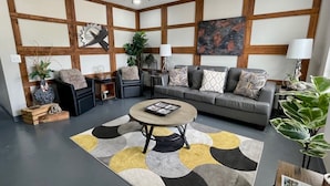 A modern living room with a gray sofa, a coffee table, and a ceiling fan. - Take a trip to the Industrial Age in this centrally-located townhome. (Springdale)