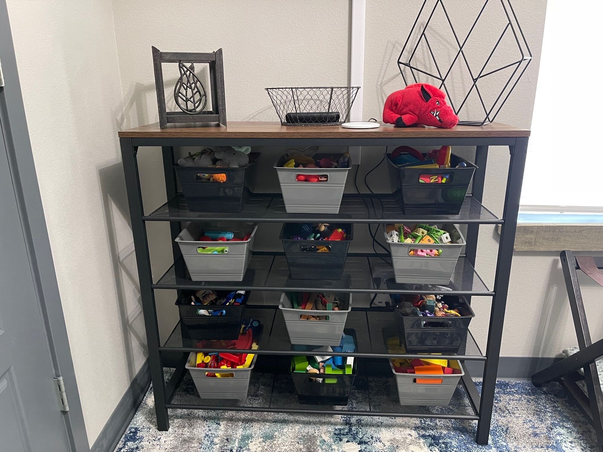A metal shelving unit with multiple storage bins containing various items.