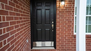A black door with a metal step and a doormat. - Take a trip to the Industrial Age in this centrally-located townhome. (Springdale)