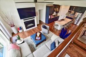 A modern living room with a fireplace, a dining area, and a kitchen.