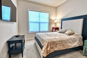 Ein Schlafzimmer mit Bett, Nachttisch, Lampe und Fenster.