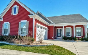 Ein rotes Einfamilienhaus mit Garage, Veranda und kleinem Vorgarten.