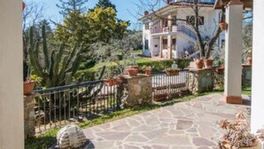 A stone-paved patio with a view of a white building with balconies, surrounded by cacti and potted plants.