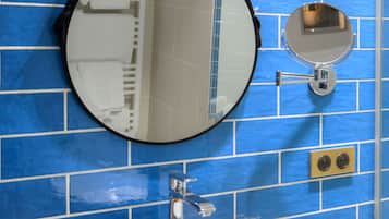 A bathroom with a large white sink, two round mirrors, and a blue-tiled wall.