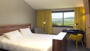 A hotel room with a large bed, a desk, a chair, and a view of the countryside. - Hotel Les Grains D'argent (Dizy)