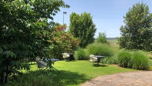 A patio area with a brick pathway, outdoor furniture, and lush greenery. - Hotel Les Grains D'argent (Dizy)