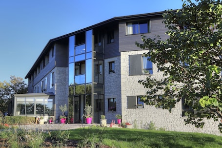 A modern two-story building with a stone facade and large windows.