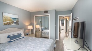 Un dormitorio con cama, lámparas de noche, un televisor y un cuadro en la pared.