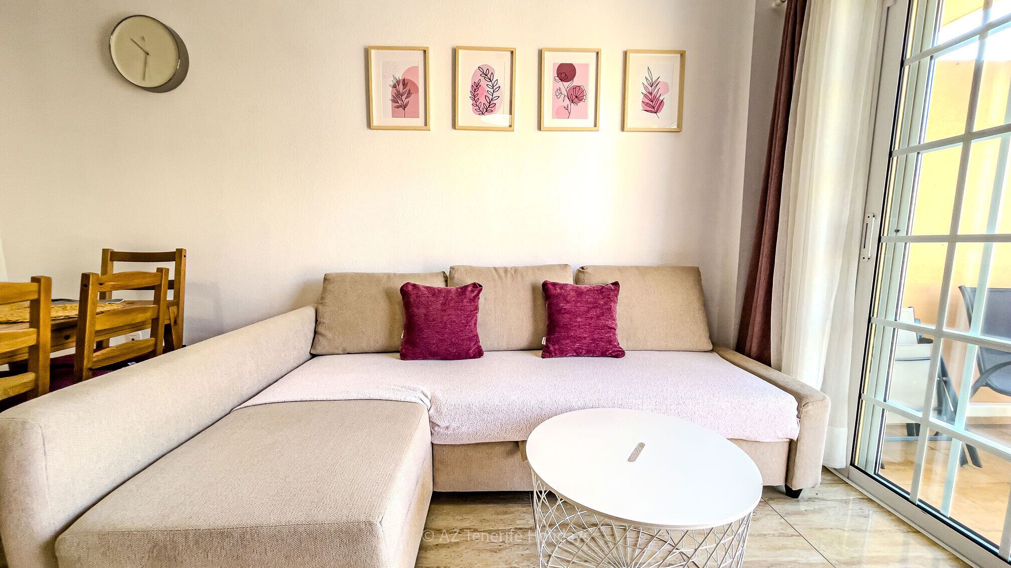 A living room with a sofa, two cushions, a coffee table, and a clock on the wall.
