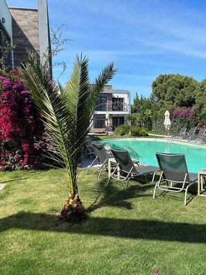 A modern two-story building with a swimming pool, surrounded by lush greenery and pink flowers. - Malta Bodrum (Bodrum)