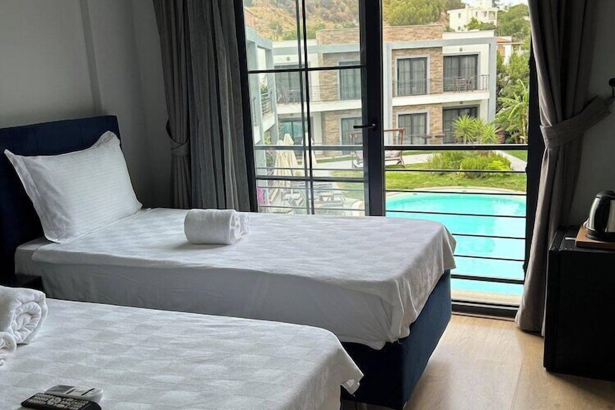 A hotel room with two beds, a view of a swimming pool, and a balcony.