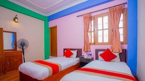 A hotel room with two single beds, a wooden wardrobe, a bedside table, a nightstand, a lamp, and a window with curtains. - Hotel om (Kathmandu)