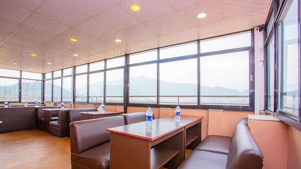 A modern meeting room with leather seating, large windows, and a view of mountains. - Hotel om (Kathmandu)