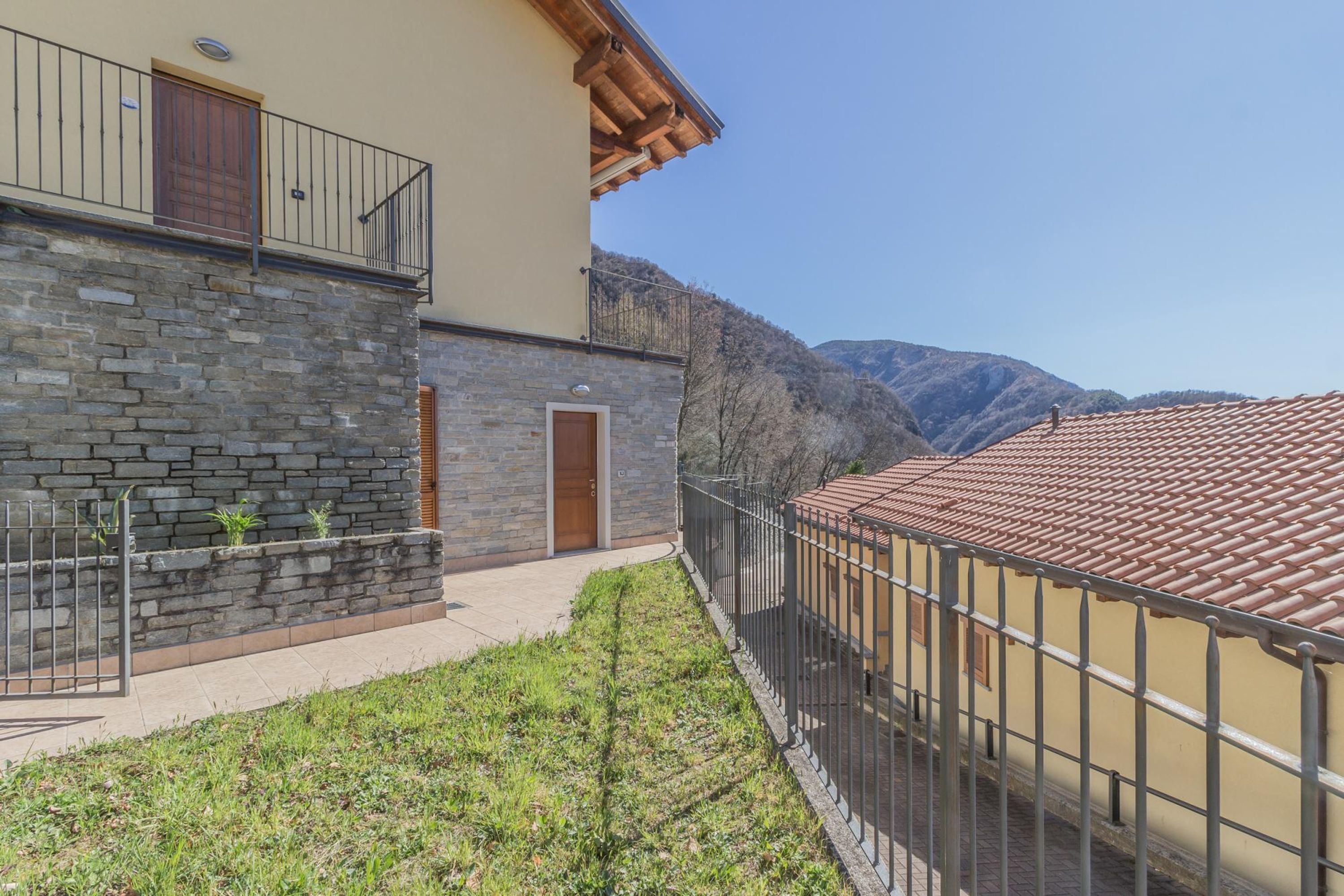 A two-story house with a stone facade, a balcony, and a view of mountains.