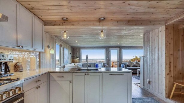 A modern kitchen with white cabinets, a central island, and pendant lighting. - Daydreamer - Beachfront! (Cannon Beach)
