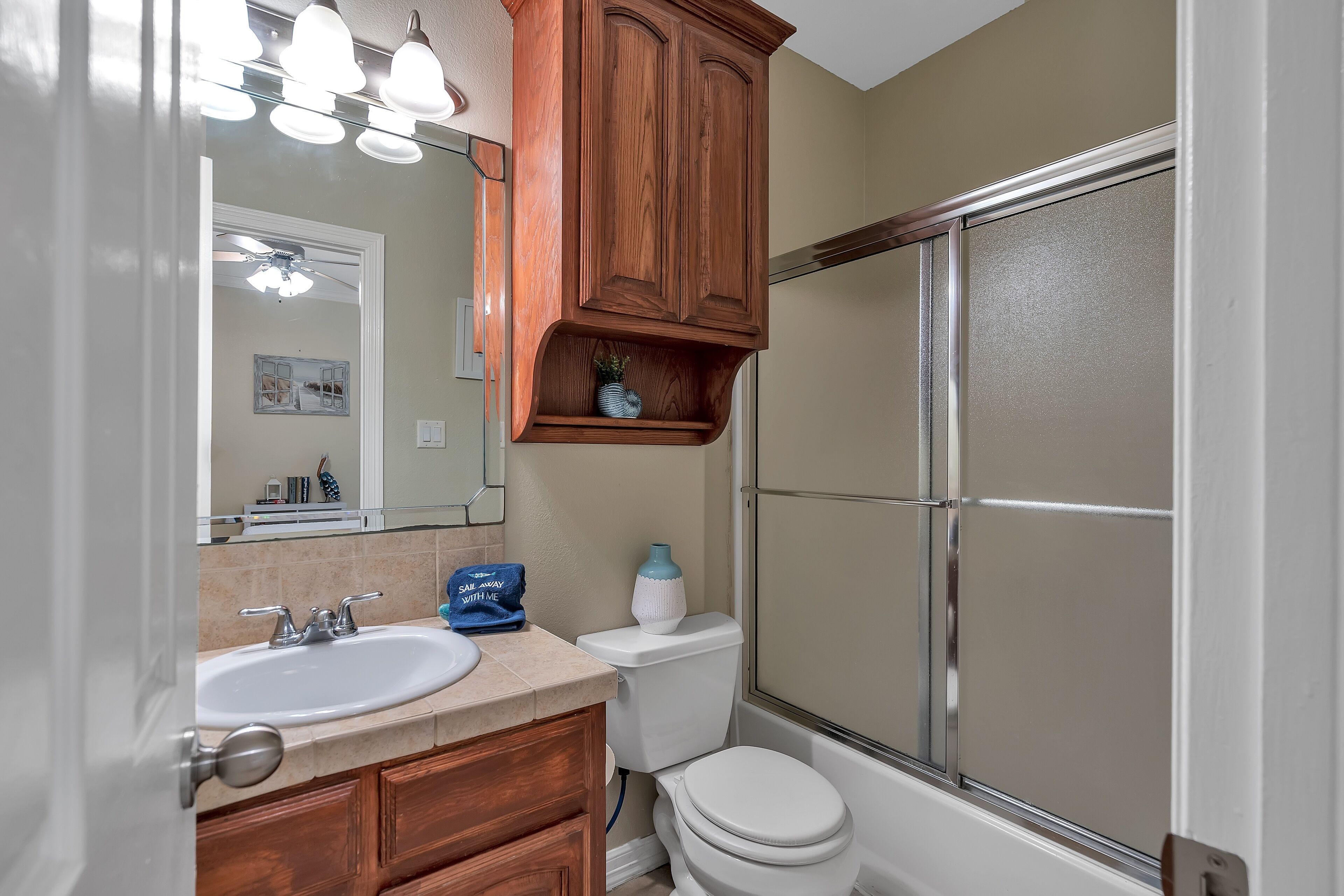 A bathroom with a sink, mirror, cabinet, toilet, and shower.