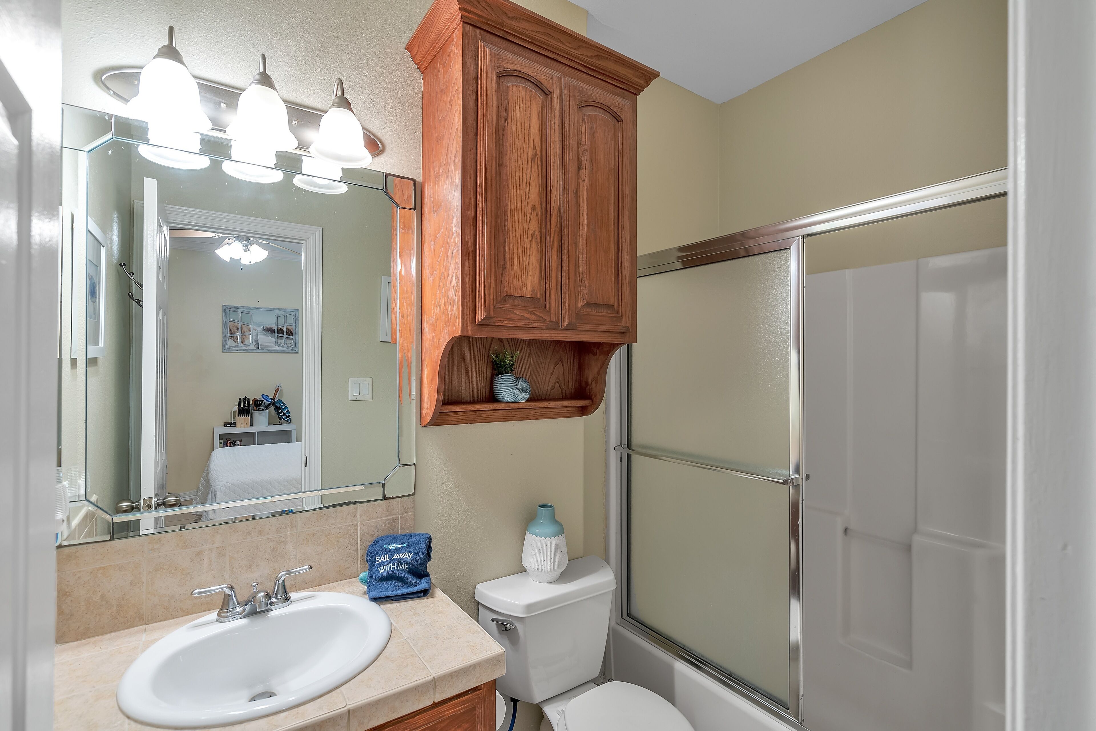 A bathroom with a white sink, a mirror, a wooden cabinet, and a shower enclosure.