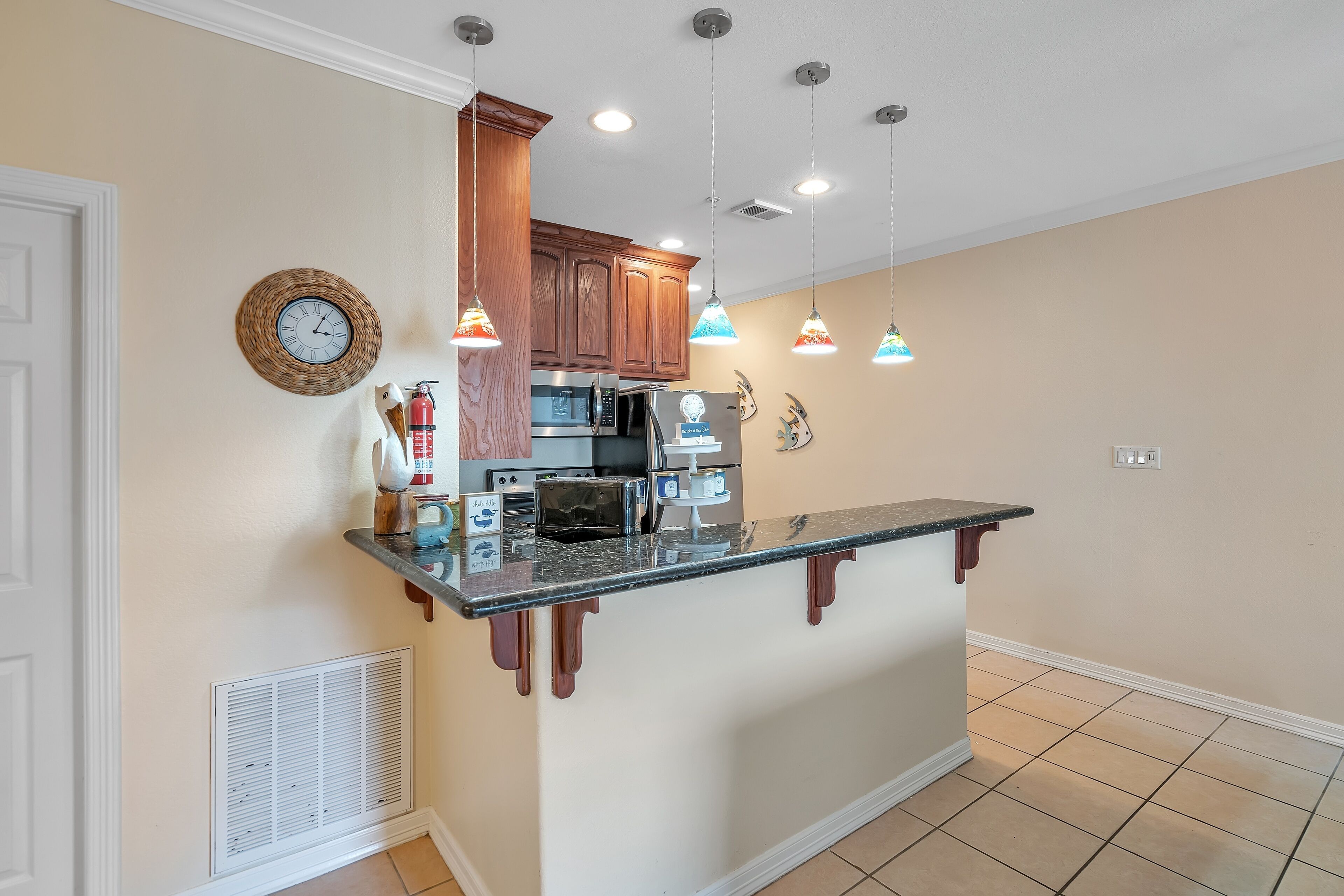 A kitchen with wooden cabinets, a microwave, a toaster, and pendant lights.
