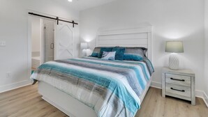 A bedroom with a bed, a nightstand, a lamp, and a sliding door to a bathroom.