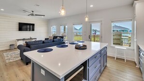 A modern kitchen with a central island, a dining area with a sofa, and a view of the outside.