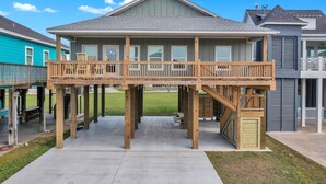 A two-story house with a wooden deck and a covered outdoor area.