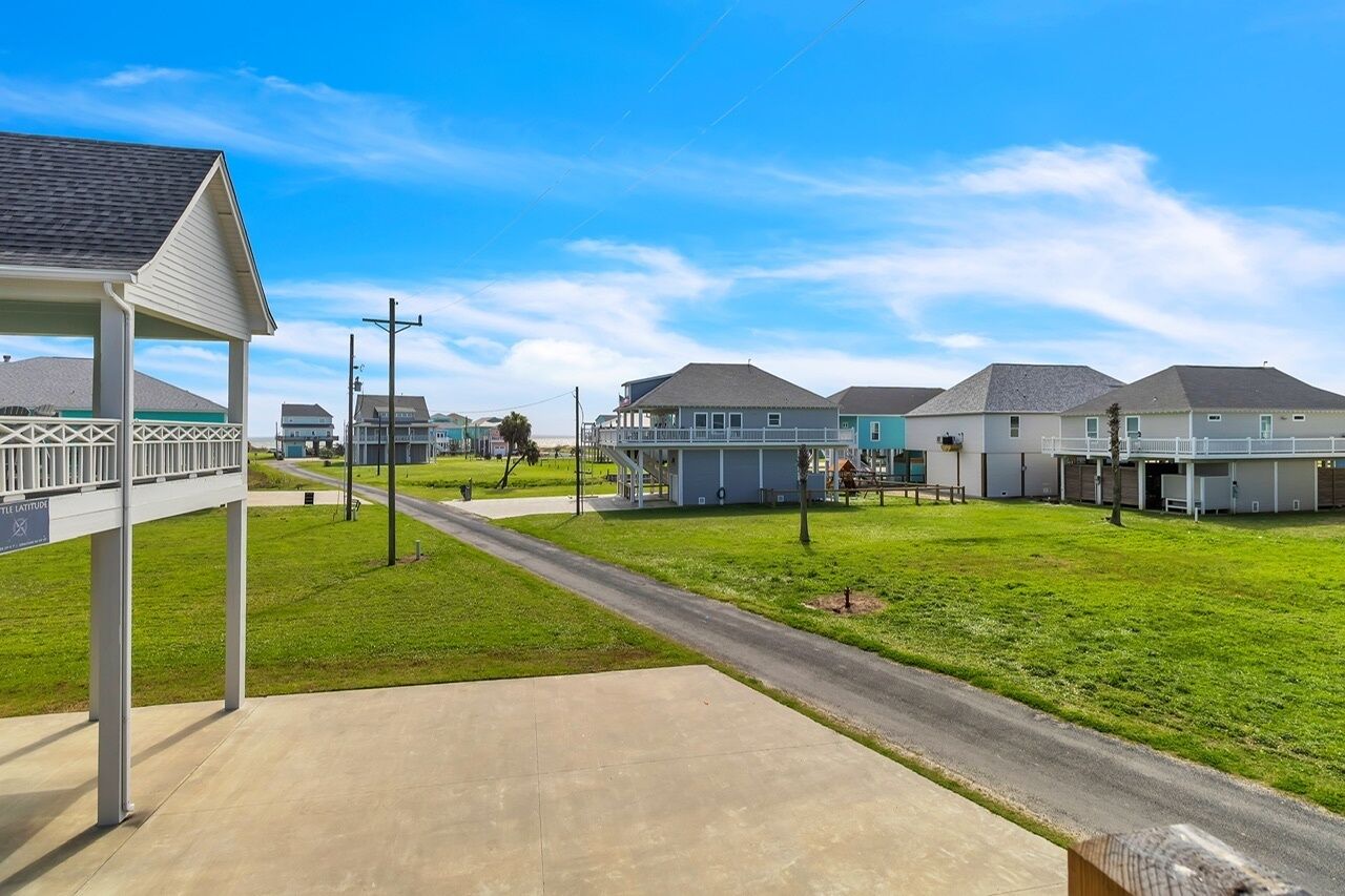 Un quartier résidentiel avec des maisons, une allée couverte et un ciel dégagé.