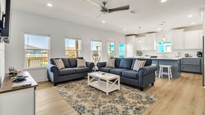 A modern living room with two sofas, a coffee table, and a kitchen in the background.