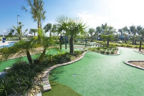 Un parcours de golf doté d’un green d’entraînement, de palmiers et d’un espace piscine.