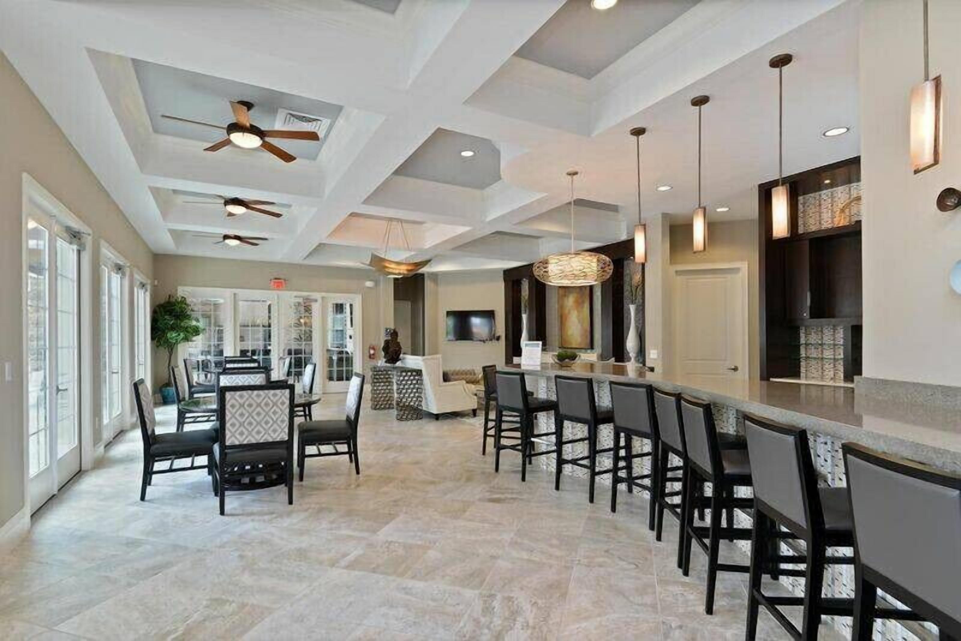 A spacious indoor area with a bar, seating, and ceiling fans.