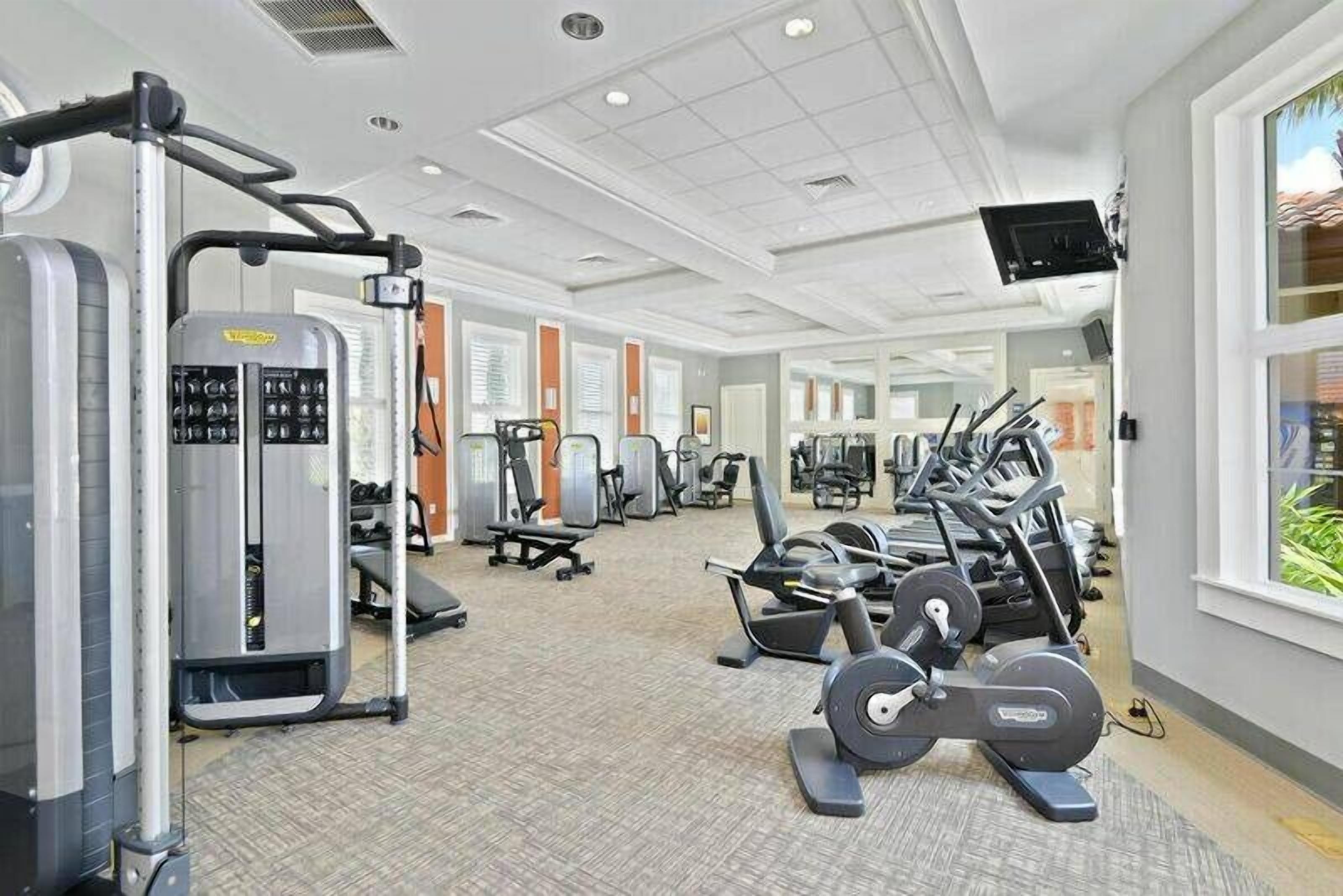 A gym with various exercise equipment, including treadmills, weight machines, and free weights.