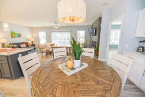 A modern kitchen with a round wooden table, white cabinets, and a ceiling fan. - Family fun-large home, beach, marina, pools (Long Neck)