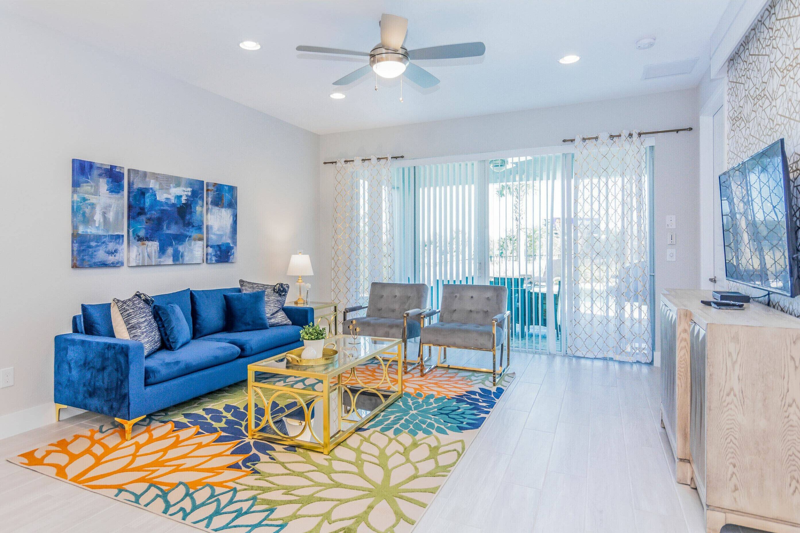 A modern living room with a blue sofa, two armchairs, a coffee table, and a TV on a wooden cabinet.