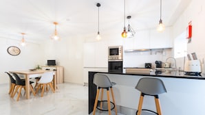 Una cocina moderna con armarios blancos, una isla central con taburetes de bar e iluminación colgante.